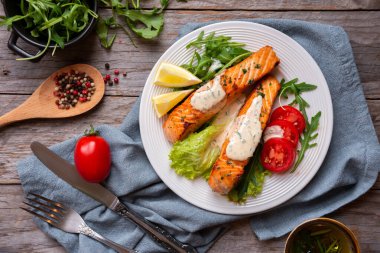 Pişmiş somon balığı fileto, otlar, limon ve sebzeler.