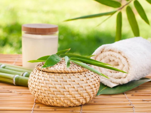 spa composition with leaves, towel and bamboo branch on green background