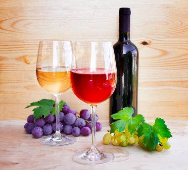 Ahşap zemin üzerinde kırmızı şarap ve üzüm.