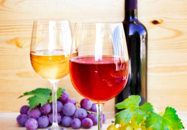 Ahşap masada kırmızı şarap ve üzüm.