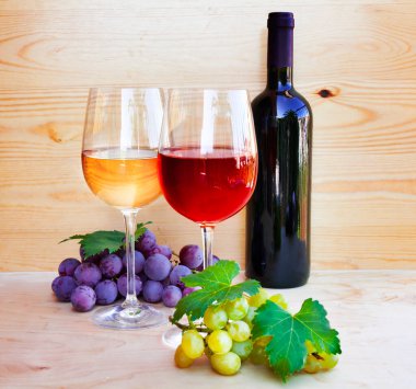 Ahşap zemin üzerinde kırmızı şarap ve üzüm.