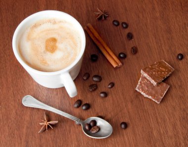 Tarçın çubuklu kahve fincanı ve ahşap arka planda anason.