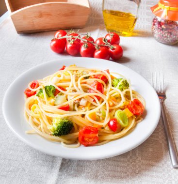 Domates soslu makarna ve beyaz tabakta taze fesleğen.