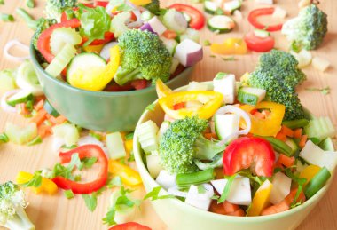 Tahta bir masadaki kaselerde taze sebzeler.