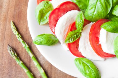 Beyaz tabakta mozzarella, fesleğen ve roka salatası.