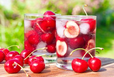 Tahta masadaki bardakta taze kırmızı kiraz suyu.