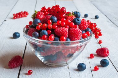 Tahta arka planda bir kasede taze meyveler.