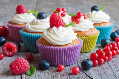 Kremalı ve böğürtlenli lezzetli kekler ahşap arka planda