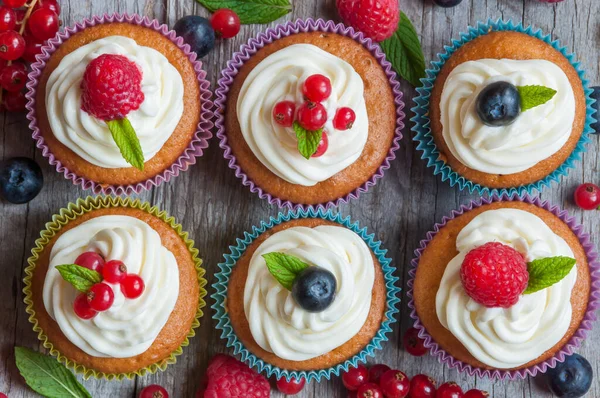 Läckra Muffins Med Grädde Och Bär Vit Trä Bakgrund — Stockfoto