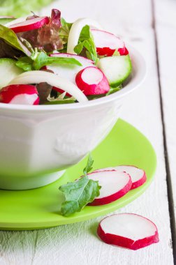 Taze sebzeli salata ve beyaz tabakta turp.