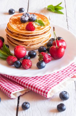 Taze böğürtlenli krep ve beyaz tabakta yaban mersini yığını.