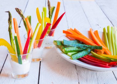 Tahta masadaki beyaz soslu taze kesilmiş sebzeler.