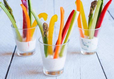 Tahta masadaki beyaz soslu taze kesilmiş sebzeler.