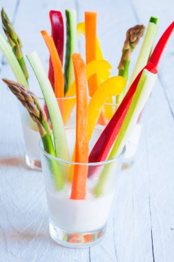 Tahta masadaki beyaz soslu taze kesilmiş sebzeler.