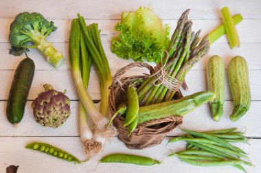 Tahta arka planda taze sebzeler ve otlar.