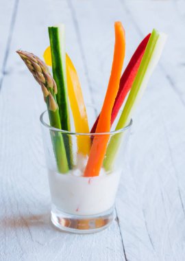 Tahta masadaki beyaz soslu taze kesilmiş sebzeler.