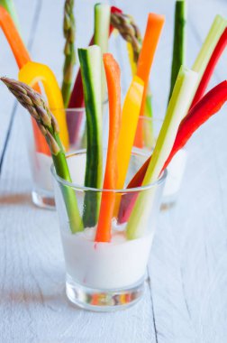 Tahta masadaki beyaz soslu taze kesilmiş sebzeler.