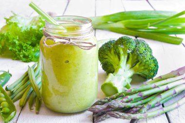 Beyaz ahşap arka planda taze sebzeli yeşil smoothie.