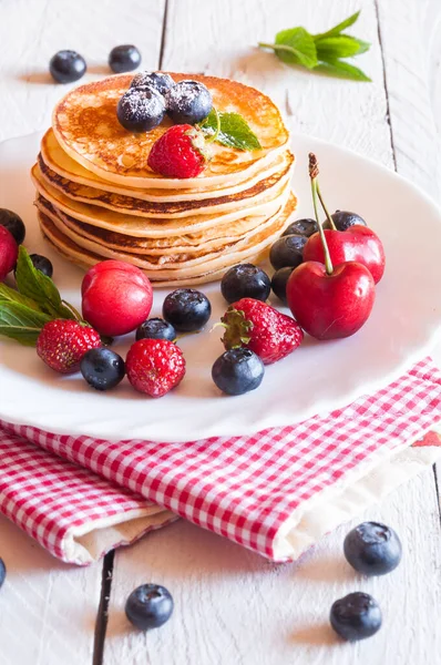 Taze böğürtlenli krep ve beyaz tabakta yaban mersini yığını.