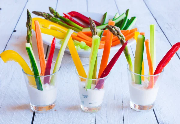 Tahta masadaki beyaz soslu taze kesilmiş sebzeler.