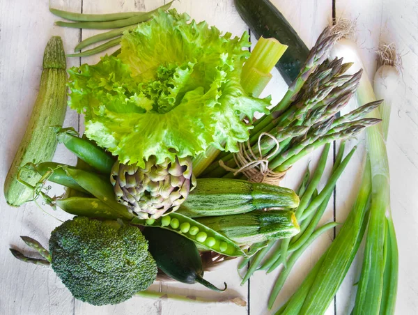 Tahta arka planda taze yeşil sebzeler ve otlar.