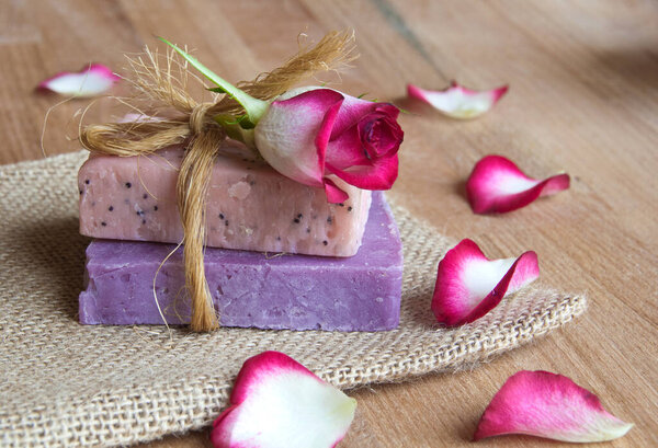 Мыло ручной работы с розой и сушеными цветами на деревянном фоне