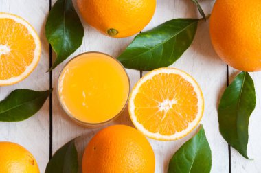 Tahta masada bir bardak portakal suyu ve taze portakallar. 