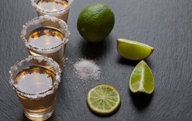 Limonlu tekila bardakları ve ahşap arka planda tuz.