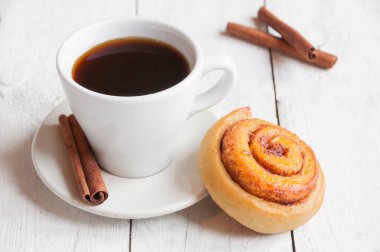 Tarçınlı bir fincan kahve ve ahşap zemin üzerinde şeker.