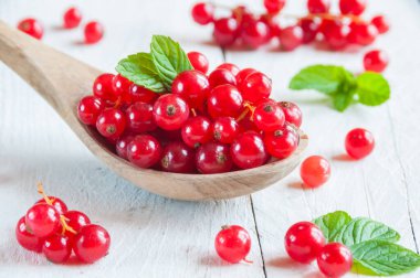 Tahta bir arka planda ahşap kaşıkta taze kırmızı üzümler.