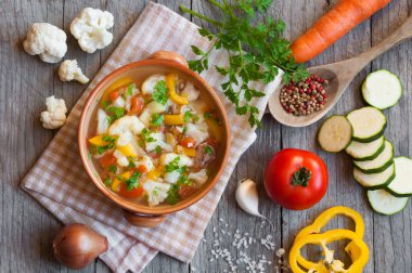 Sebzeli ev yapımı sebze çorbası ve ahşap arka planda baharatlar.