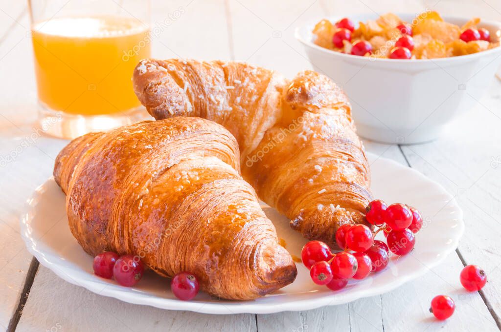 breakfast with fresh croissants and juice on wooden table