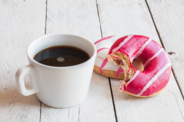 Ahşap arka planda bir fincan kahve ve çörek