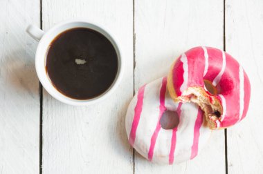 Beyaz ahşap arka planda bir fincan kahve ve çörek.