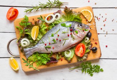 Sebzeli taze balık ve ahşap arka planda baharatlar.