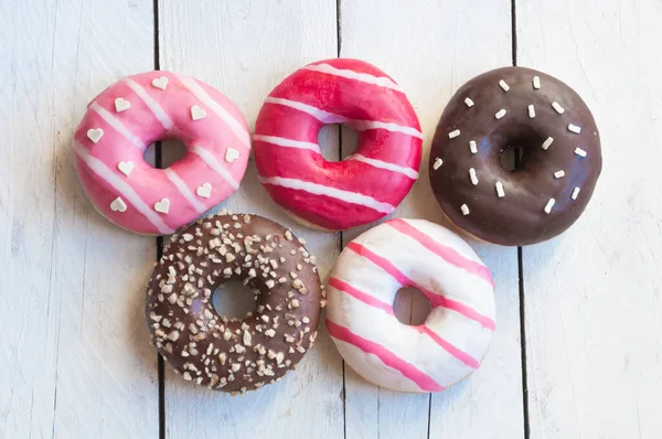 donuts with pink and chocolate icing on wooden background