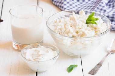 Beyaz ahşap arka planda yoğurt ve süt ile süzme peynir. seçici odak