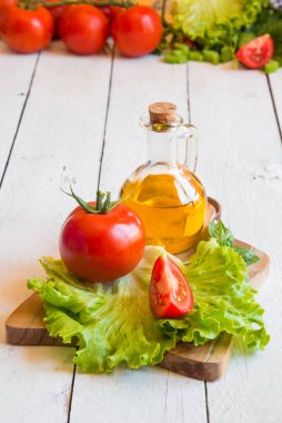Ahşap arka planda zeytinyağı, domates, marul ve fesleğen.
