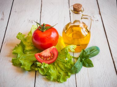 Ahşap arka planda zeytinyağı, domates, marul ve fesleğen.