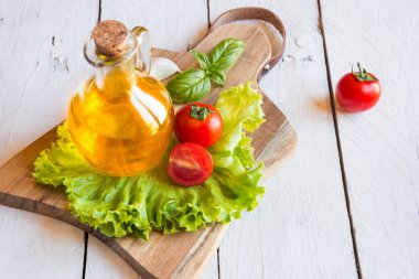 Ahşap arka planda zeytinyağı, domates, marul ve fesleğen.