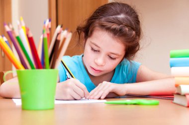 Evde kalemlerle resim yapan sevimli küçük bir kız. 