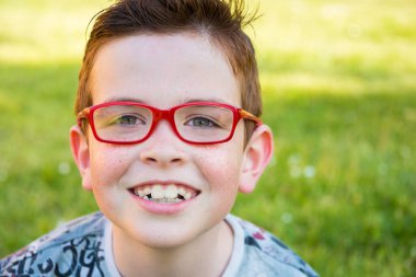 Yaz parkında kırmızı gözlüklü şirin bir çocuğun portresi.  