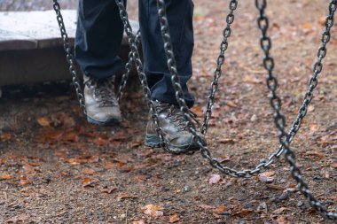 Yürüyüş botlarıyla zincire vurulmuş ayaklar ormandaki yaprakların üzerinden yere değmeden dengeleniyor.