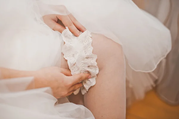 Die Braut kleidet einen Schmuck auf einen Fuß. — Stockfoto