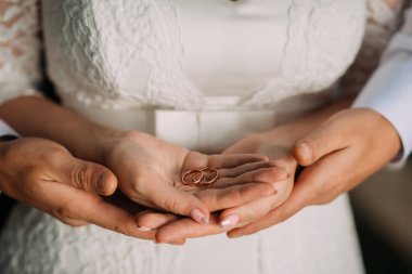 Alyansları olan yeni evli çiftin ellerini nazikçe kucaklayın..