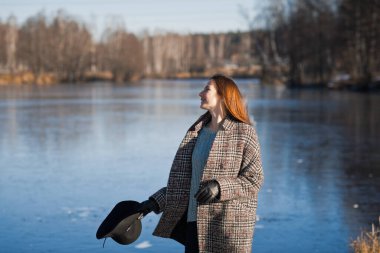 Eriyen karın arka planına karşı şapkalı ve yarım ceketli bir kızın fotoğrafı..