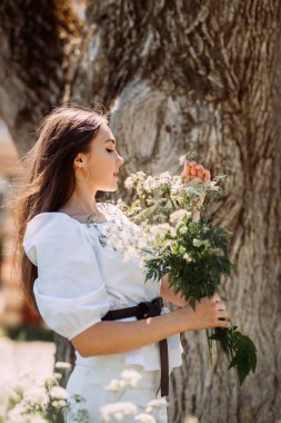 Bir yaz parkında elinde papatya buketiyle neşeli bir kızın yürüyüşü..