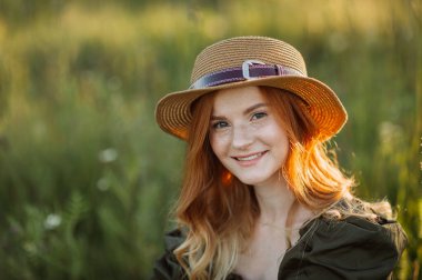 Yazın tarlada karahindibaların arasında kızıl saçlı bir kız..