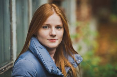 Tuğla duvarın yanında kızıl saçlı bir kız.