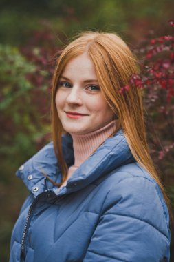 Kızıl saçlı bir kız güzel çalıların arasında yürüyor..